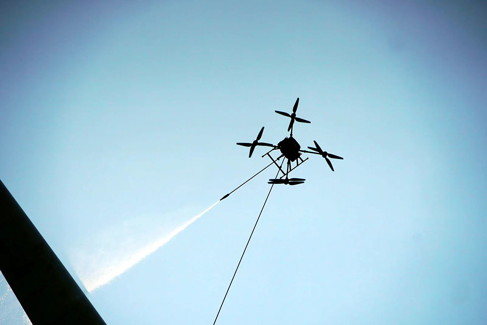 Reinigingsdrone van SkyDrone spuit water tegen een blauwe lucht